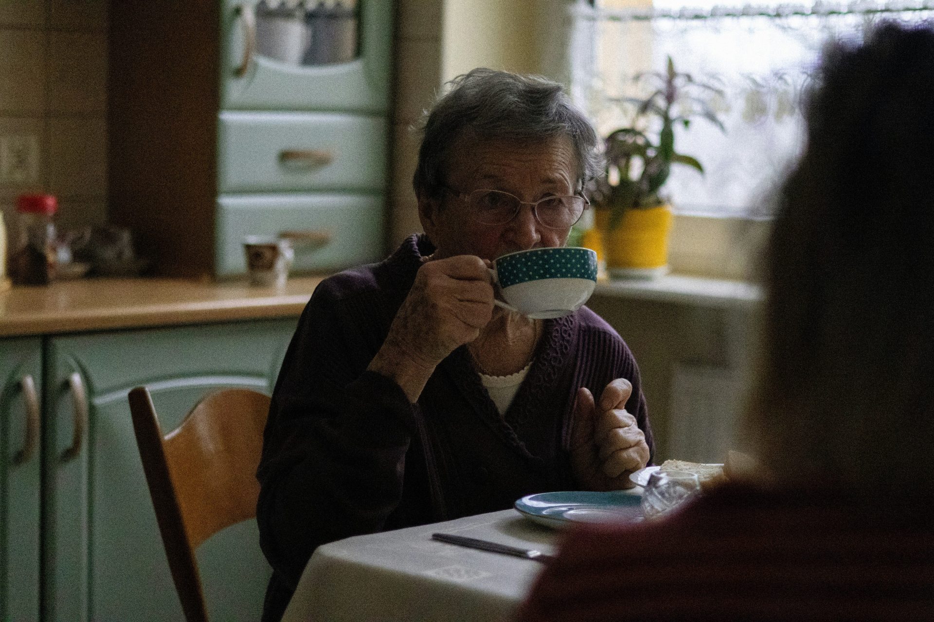 a woman sitting at a table drinking a cup of coffee
